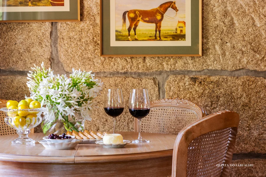 Wine glasses, fresh flowers, and a wooden table against the quinta’s old stone walls