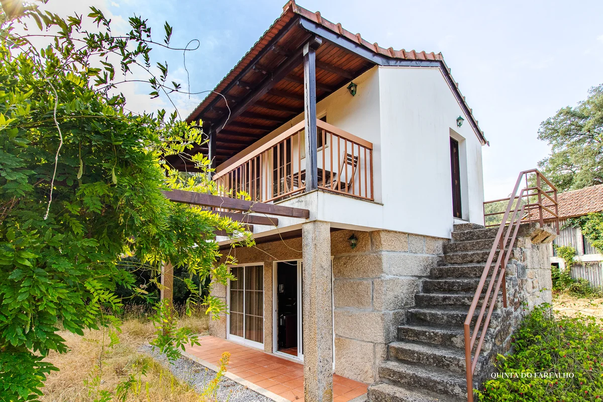 Traditional stone walls, a timber balcony, and greenery at Quinta do Farfalho