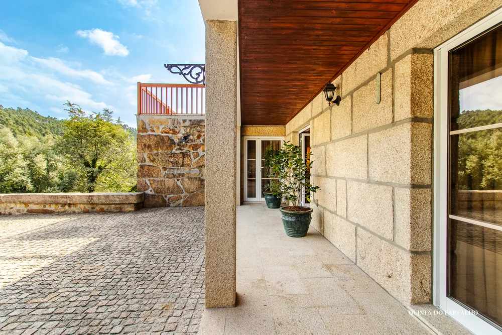 A shaded stone terrace looking out towards the green Portuguese countryside