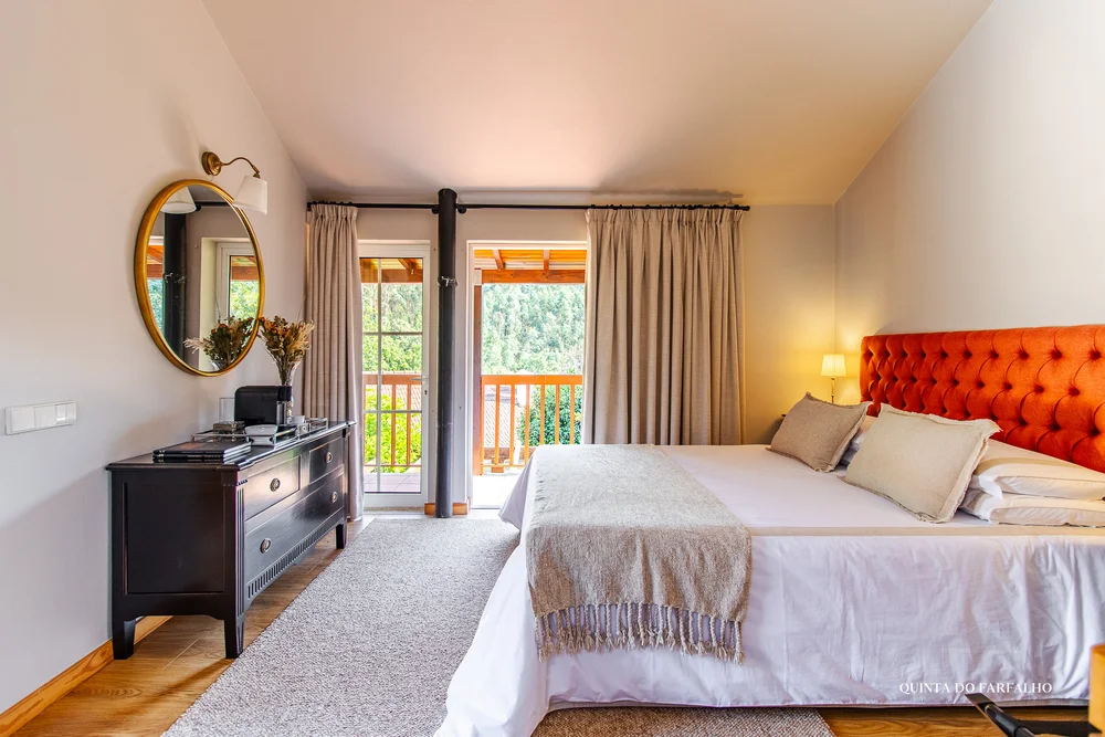 A sunlit bedroom with an orange headboard and doors opening onto the garden